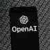 The OpenAI logo appears on a mobile phone in front of a computer screen with random binary data, Thursday, March 9, 2023, in Boston. (AP Photo/Michael Dwyer)